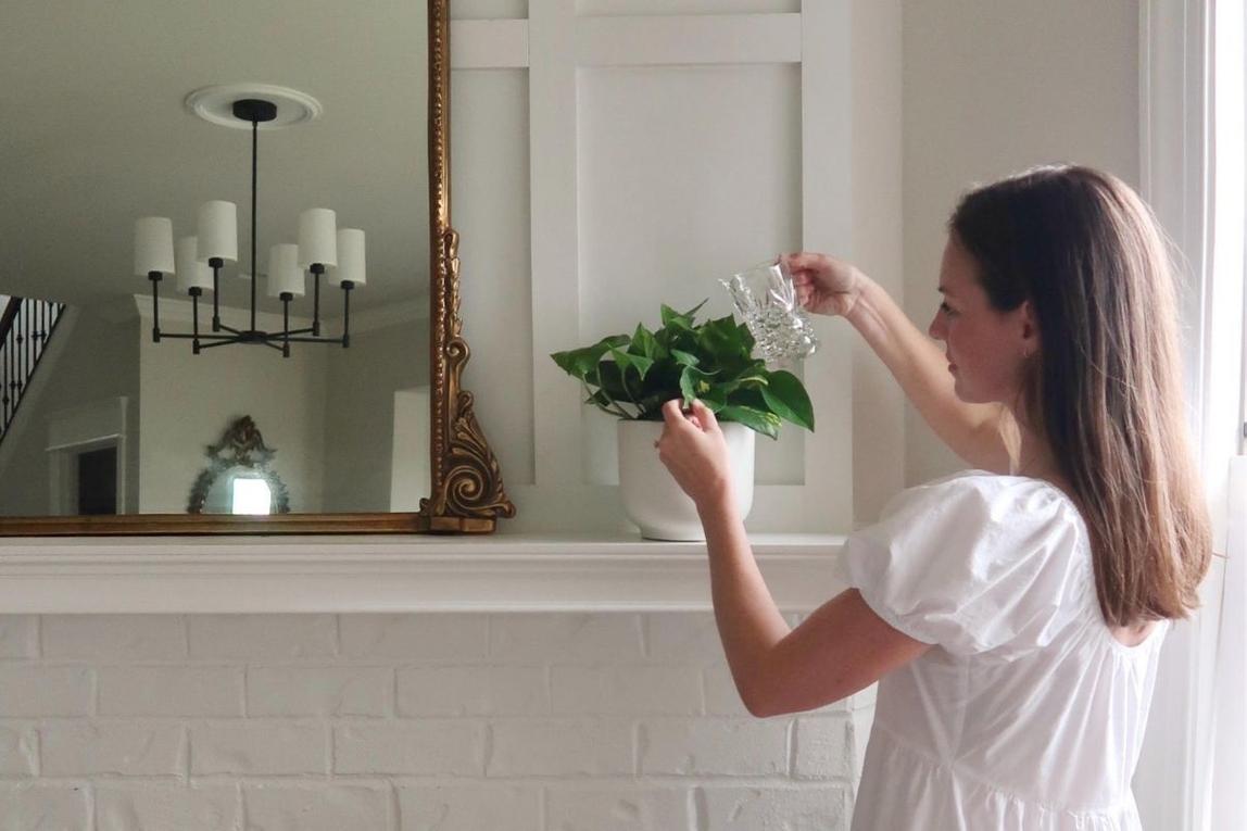 Woman caring for a Pothos plant on a mantle